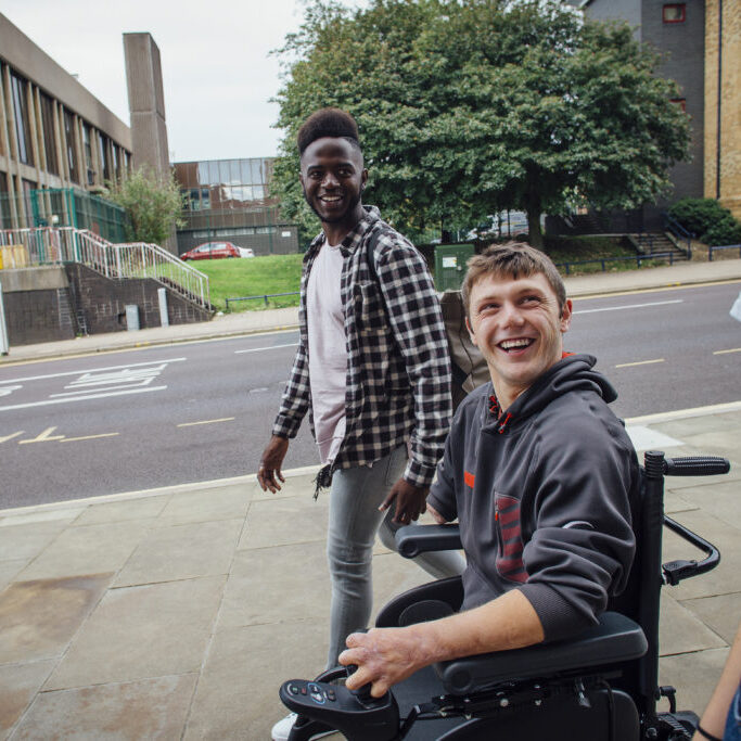young man in power wheelchair with two friends